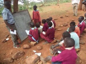 A teacher handling learners outside a classroom at a school in Northern Kenya 